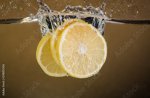 lemon slices are thrown into the water on a yellow background and splash