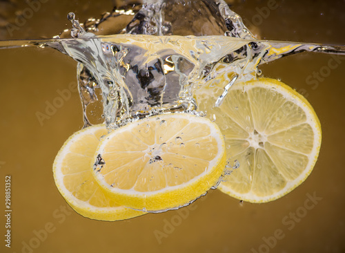 lemon slices are thrown into the water on a yellow background and splash