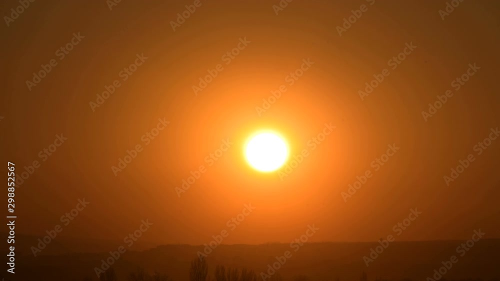 Timelapse of the setting sun behind the clouds at sunset over the small town. Swirling clouds before sunset. Low key Timelapse of the setting sun behind the clouds at sunset over the small town. Swirling clouds before sunset. Low key
