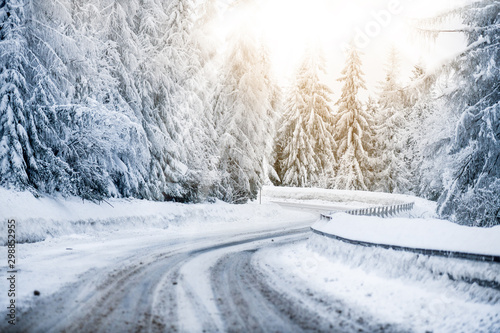 Winter beautiful snowy road snow or landscape forest and trees covered with snow. Yellow sun shine lights in background.
