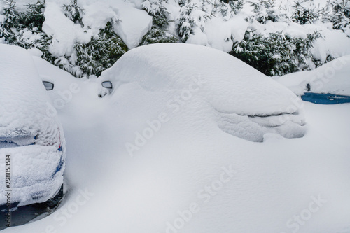 Cars covered with heavy white snow on calamity road. Winter car concept in storm or blizzard. © Milan