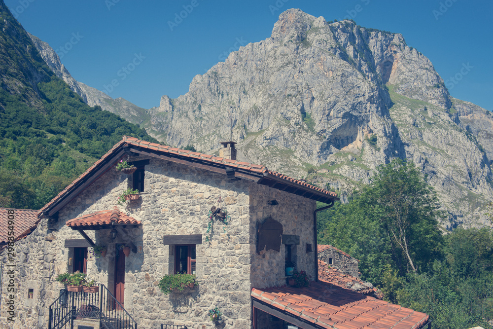 STONE HOUSE WITH ROOF OF TILES WITH HIGH MOUNTAINS OF BACKGROUND ON A CLEAR DAY WITH BLUE SKY