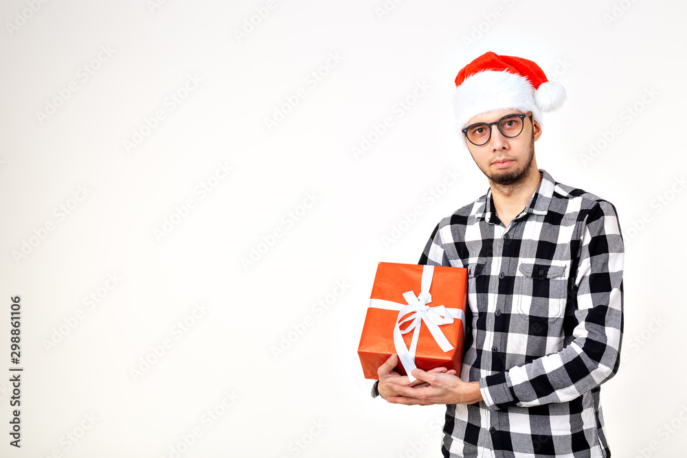 Holidays and presents concept - Funny man in Christmas hat holding gift box on white background with copy space