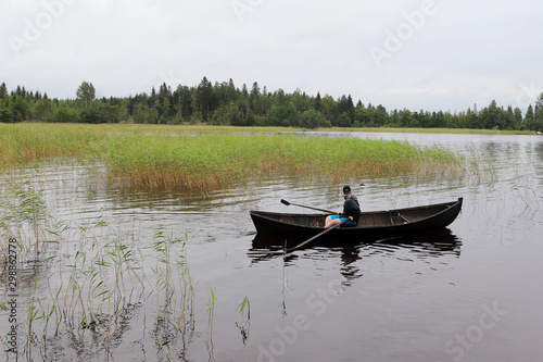 Canvas Print Boy rowing boat at Lake Saimaa, Finland