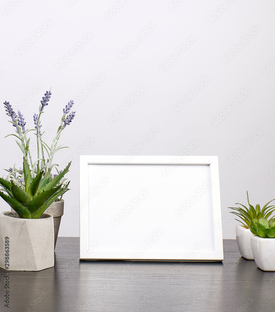 empty white frame, flowerpot with flower on a black table empty white frame, flowerpot with flower on a black table
