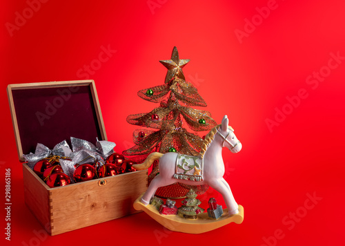 Festive composition with Christmas toys and a horse on a red background.