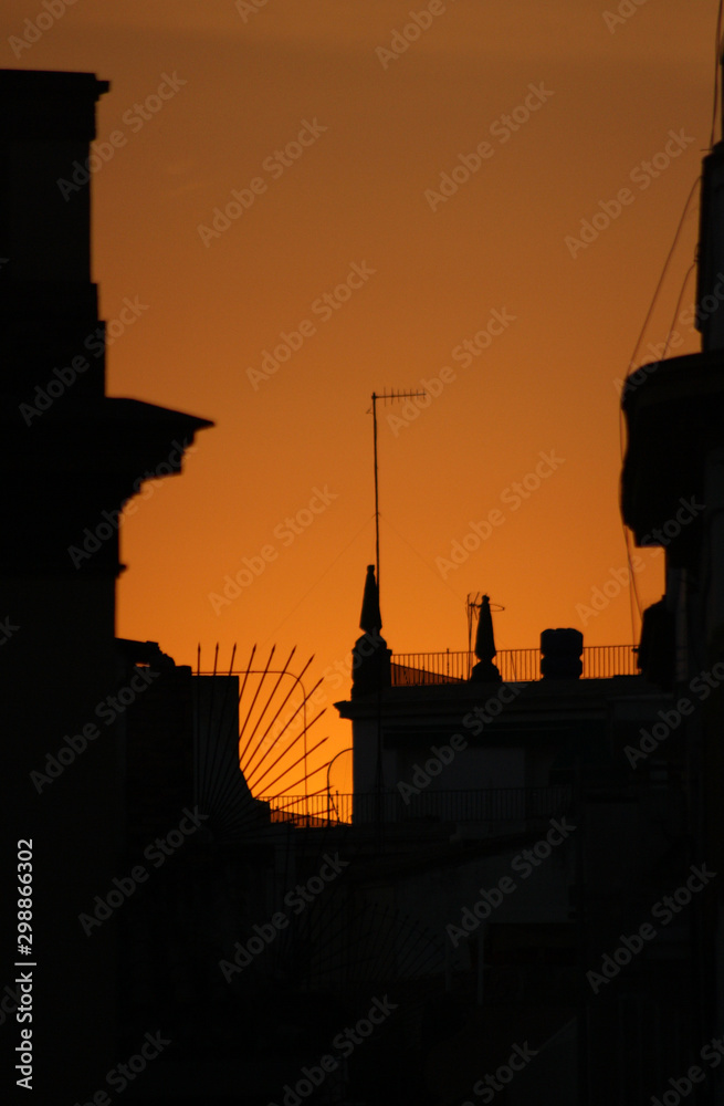 Puesta de sol anaranjada con silueta de casas