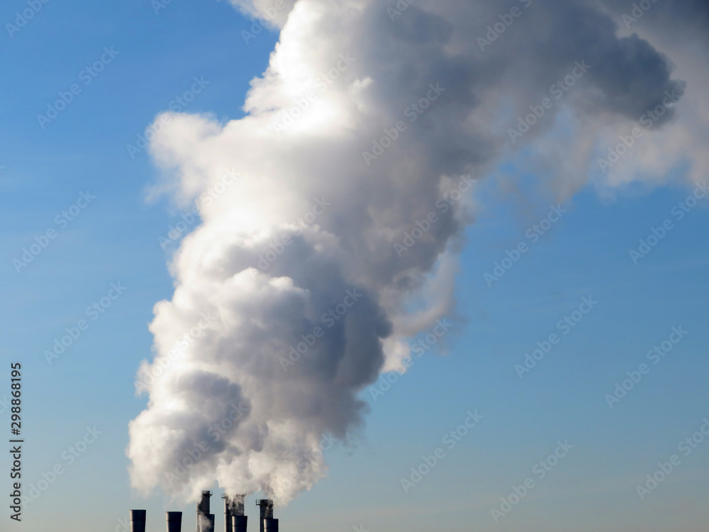 Air pollution, smoke from the chimneys on blue sky background. Concept of industry and ecology, steam plant, heating season, global warming