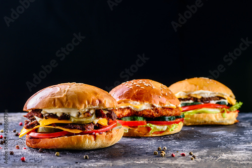 Low angle front view on three delicious chicken, beef and shrimp burgers photo