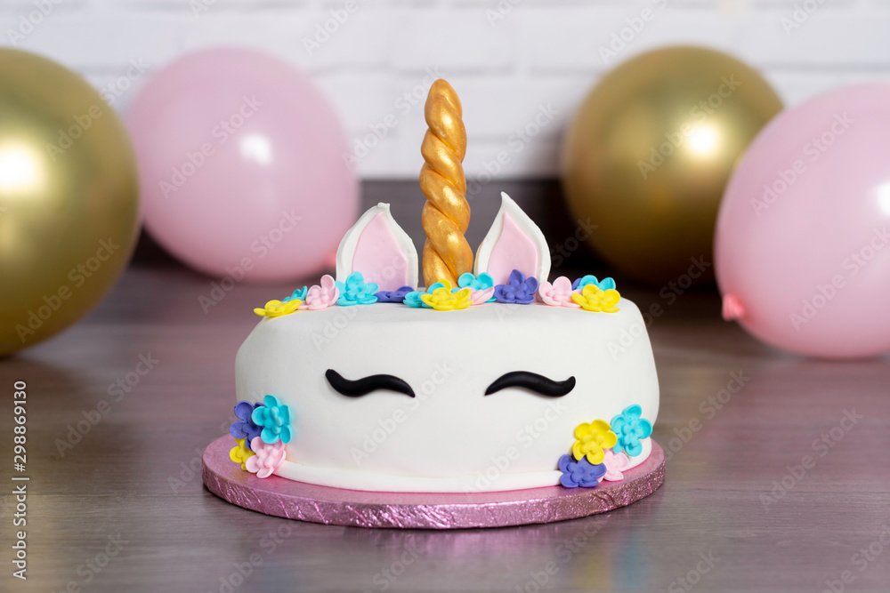 Close up beautiful homemade cake in the form of a unicorn with cream colored flowers surrounded by balloons. Smash cake unicorn, birthday celebration. Pastel colors. Close up beautiful homemade cake in the form of a unicorn with cream colored flowers surrounded by balloons. Smash cake unicorn, birthday celebration. Pastel colors.