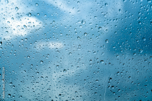 Fresh water drops after raining on blue glass window background in car.