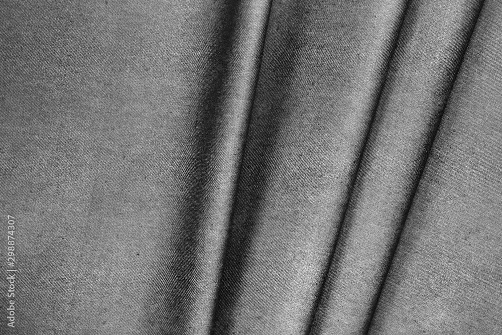Fototapeta premium Gray woolen folded fabric with folds and waves, closeup, background of the folded fabric