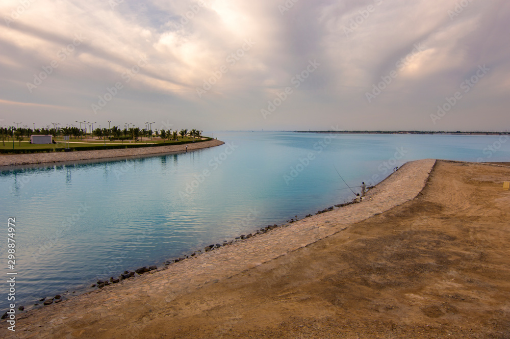 Red sea beach scene, Yanbu, Saudi Arabia.  Amazing artificial island and beach have been shown. Blue quite sea body extend to the horizon. Gorgeous cloudy sky appears. Fishermen relax while hunting.
