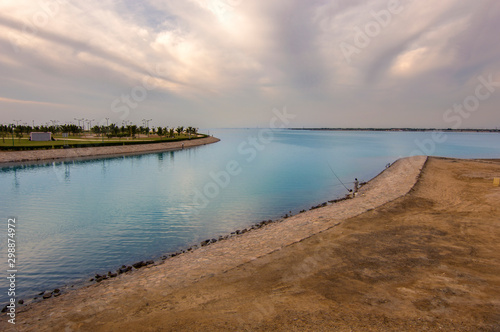 Red sea beach scene, Yanbu, Saudi Arabia. Amazing artificial island and beach have been shown. Blue quite sea body extend to the horizon. Gorgeous cloudy sky appears. Fishermen relax while hunting.