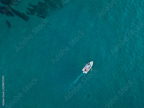 Aerial view of a rowing boat seen from above, powered by an engine. Blue sea that surrounds a boat that crosses it. People inside a boat. 10/22/2019. Pizzo Calabro, Calabria, Italy