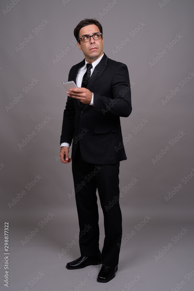 Full body shot of handsome Persian businessman using phone Full body shot of handsome Persian businessman using phone