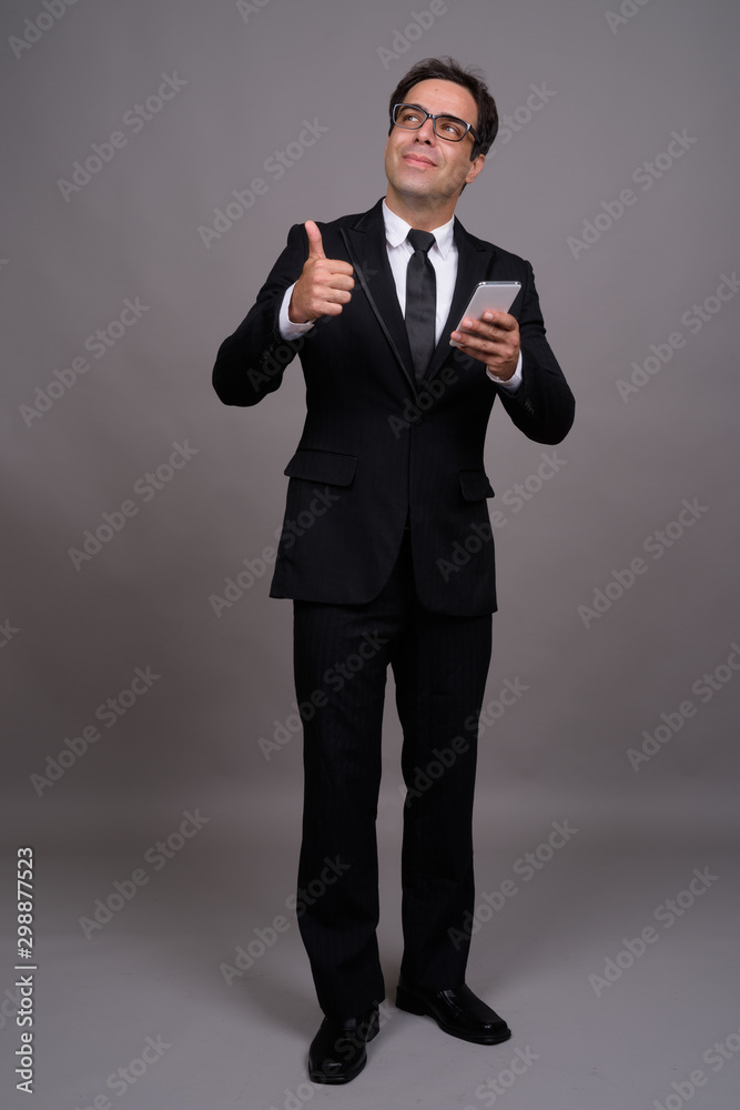 Full body shot of handsome Persian businessman using phone Full body shot of handsome Persian businessman using phone