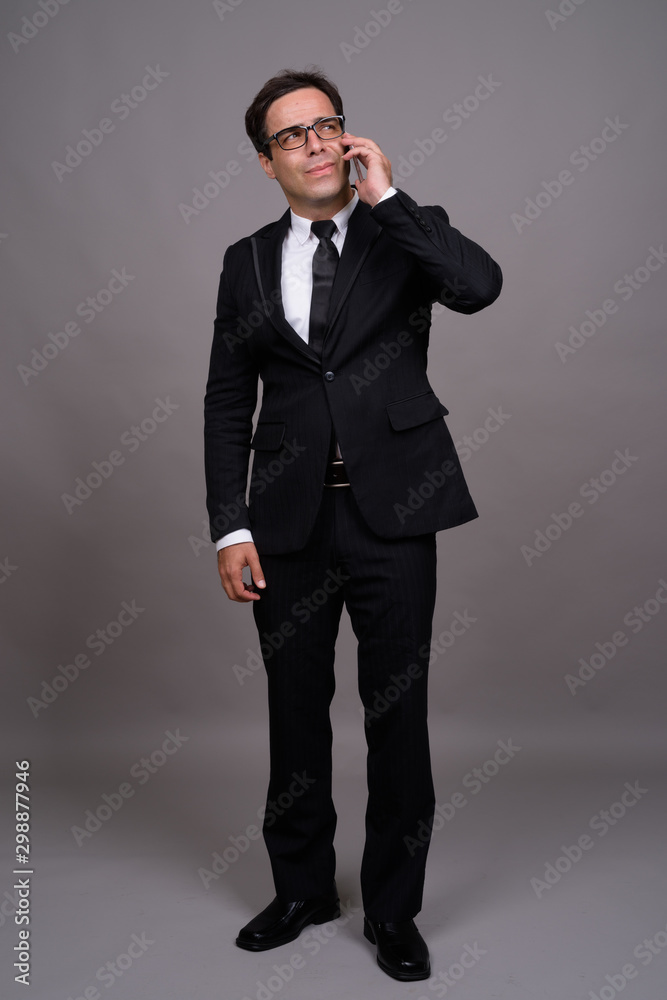 Full body shot of handsome Persian businessman using phone Full body shot of handsome Persian businessman using phone