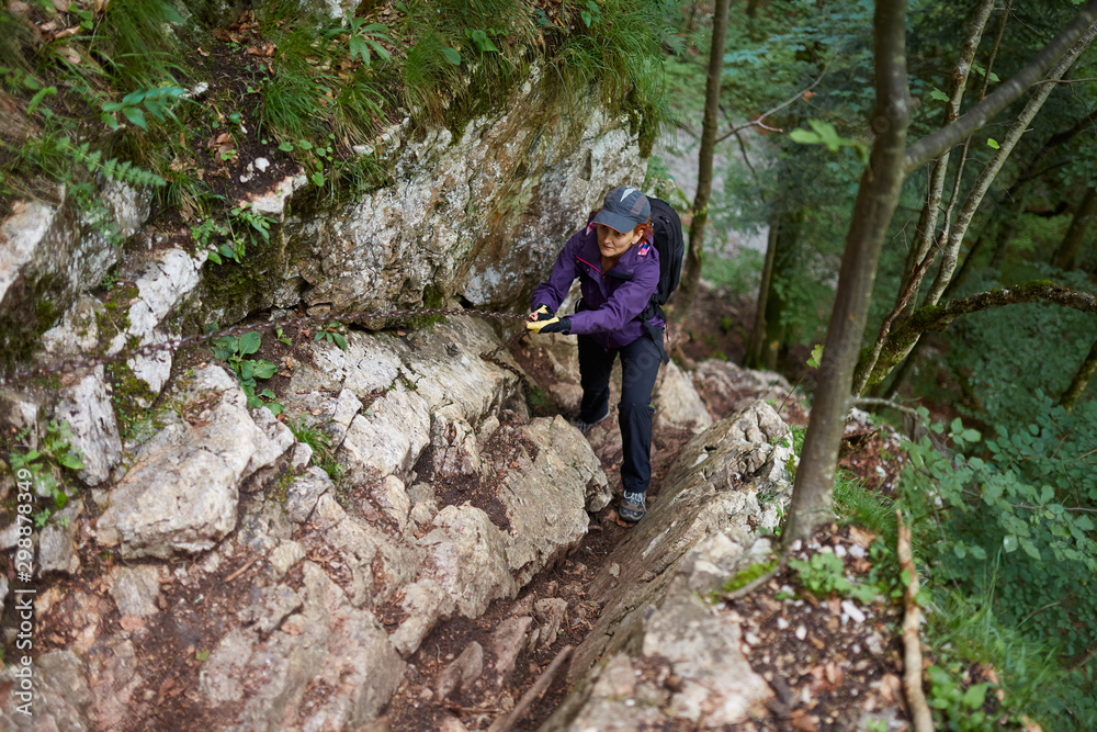 Backpacker lady on a safety chain in the mountains