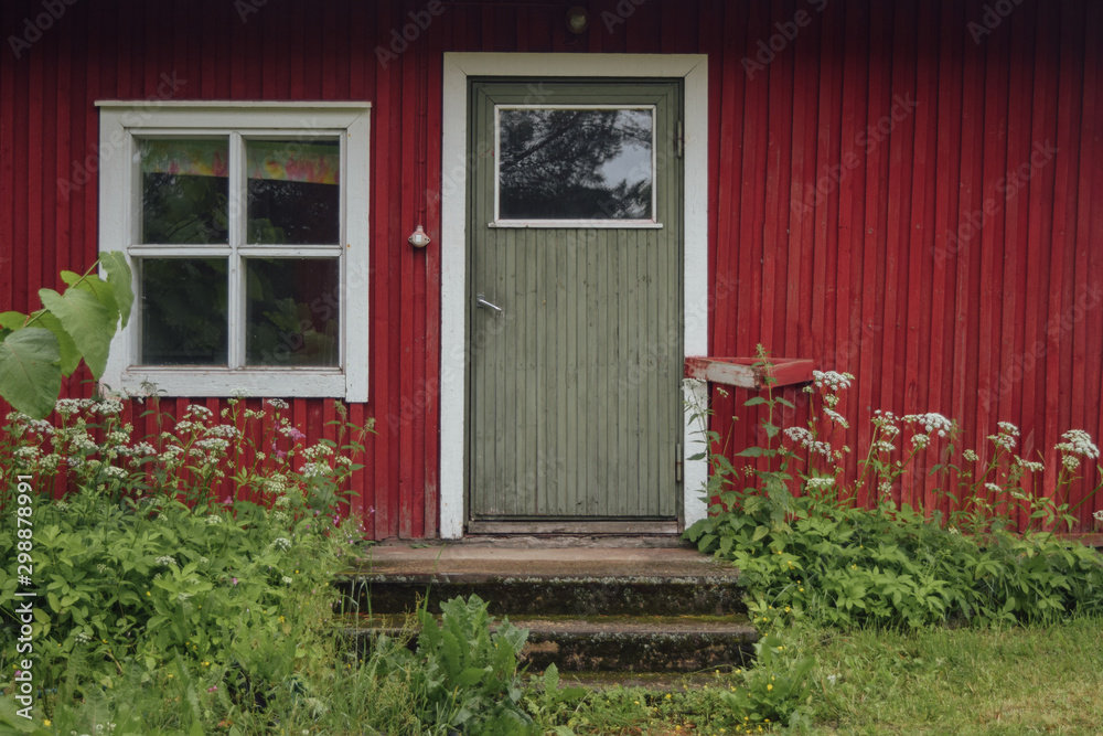 Entering to the red barn at finnish countryside strawberry farm, window and door with doorstep, summer misty day, green grass Entering to the red barn at finnish countryside strawberry farm, window and door with doorstep, summer misty day, green grass