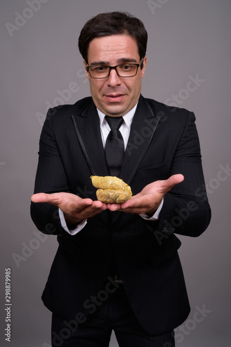 Disgusted Persian businessman with eyeglasses holding poo