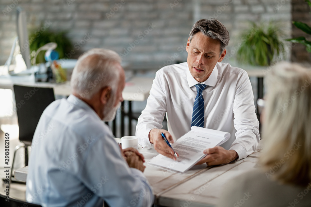 Insurance agent and senior couple analyzing terms of a contract while meeting in the office. Insurance agent and senior couple analyzing terms of a contract while meeting in the office.