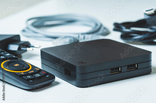 TV set-top box and all the necessary wires to connect it on a white background, selective focusing