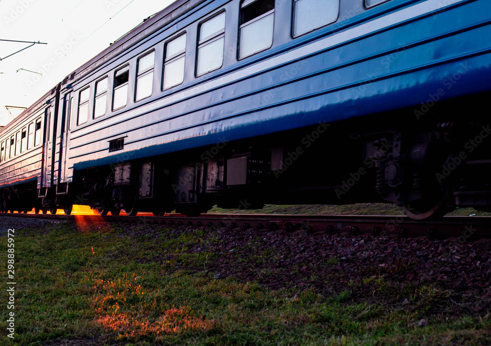 Obraz premium The train travels by rail against the background of the rays of the sun. International passenger train schedule concept, copy space