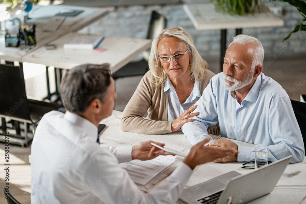 Senior couple talking to real estate agent on a meeting in the office. Senior couple talking to real estate agent on a meeting in the office.