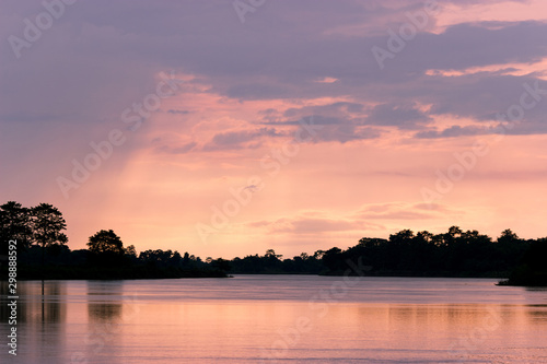 landscape of warm sunset on the river coast, pink and orange colors of the sky