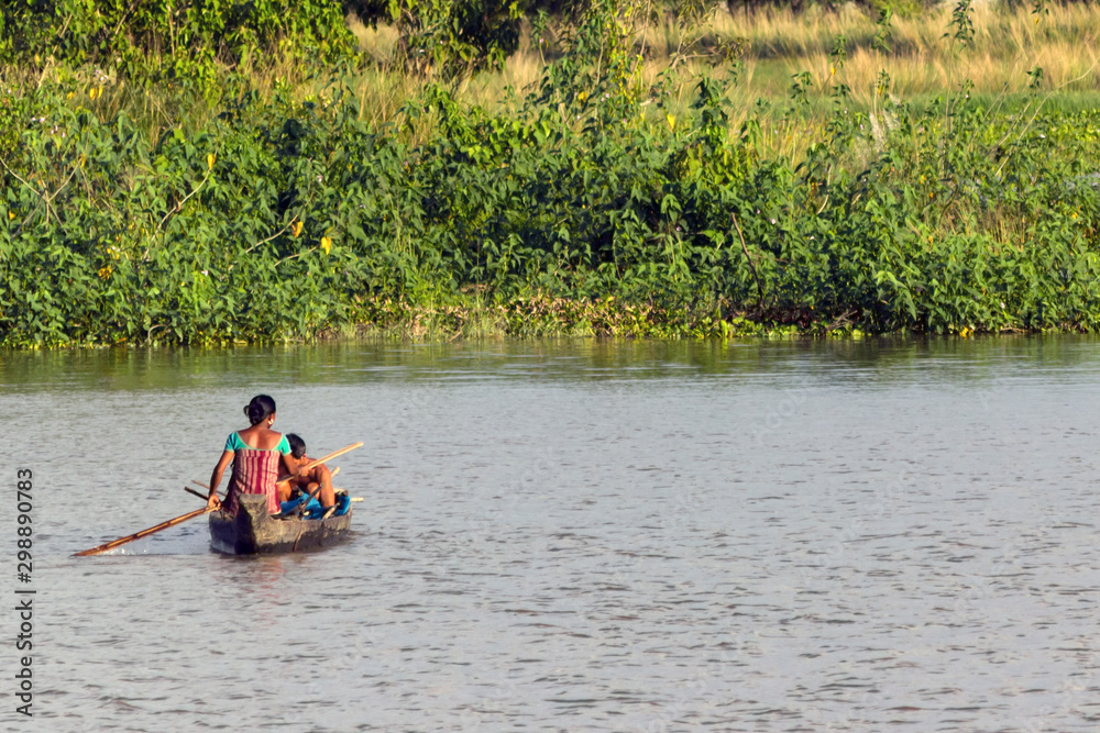 A young man and a old woman swim in a canoe on the river, a woman rowing an oar. Exploitation of women's power