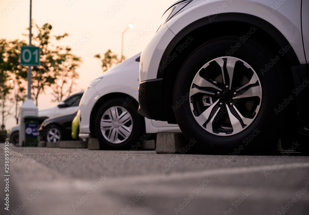 Many cars are parked in a large parking lot. Arranged in a long line Was the time when the sun was setting