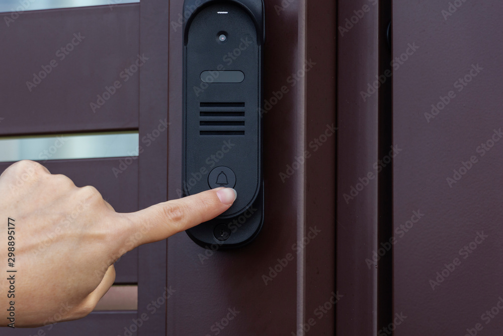 A woman presses the bell button on the front door A woman presses the bell button on the front door