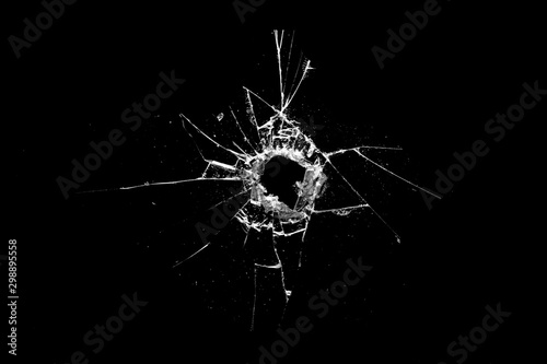 Foto hole in the glass with cracks isolated on a black background