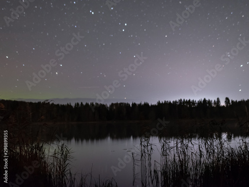 landscape with a beautiful colorful night sky and stars, reflection on lake, blurred black ground