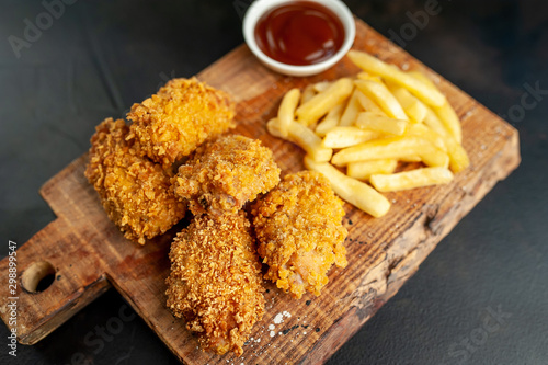 fried chicken with french fries and food nuggets - on stone background