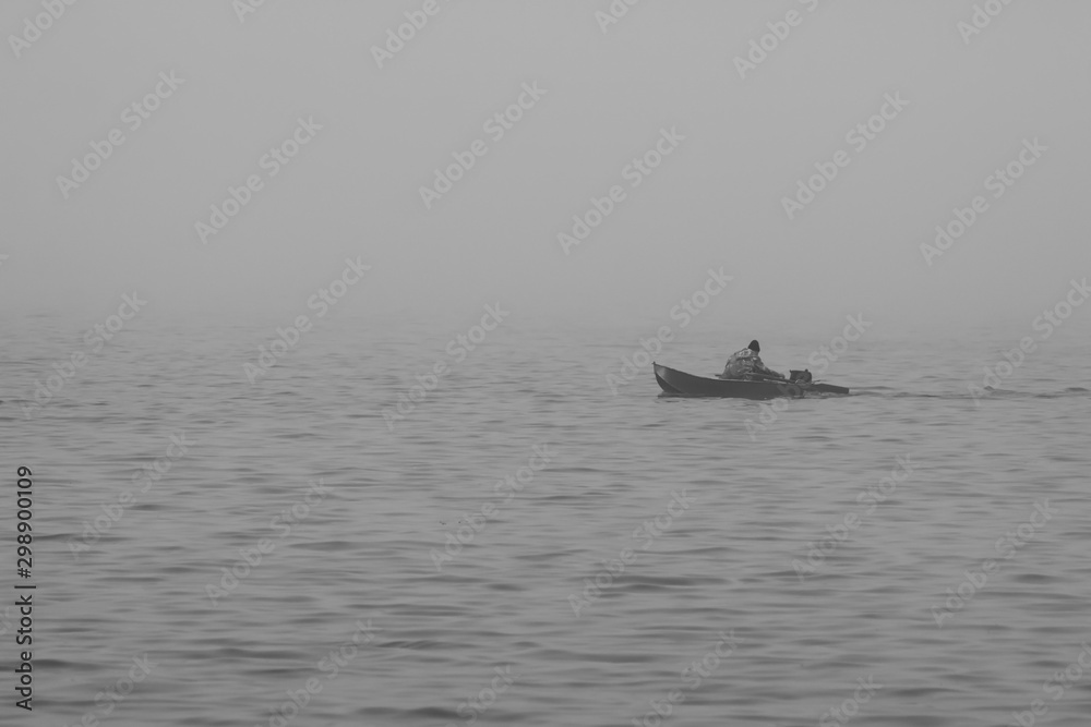A man floats on an old boat in the fog
