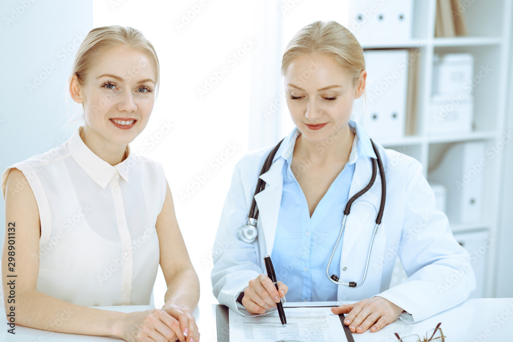 Doctor and patient talking in hospital office while sitting at the desk. Health care and client service in medicine Doctor and patient talking in hospital office while sitting at the desk. Health care and client service in medicine