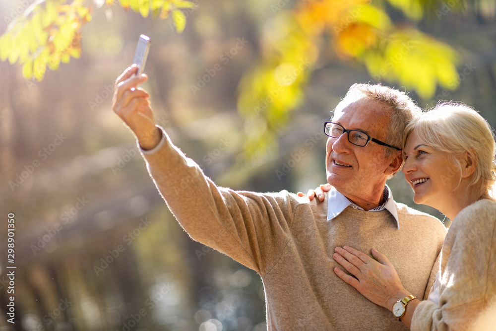 Naklejka premium Senior couple taking selfie with smartphone in park
