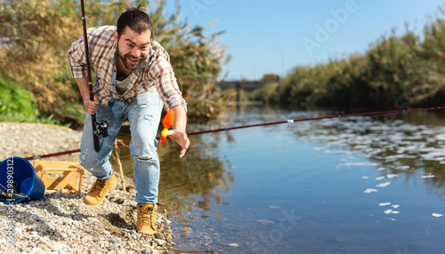 Happy fisherman pulls fish out of the river