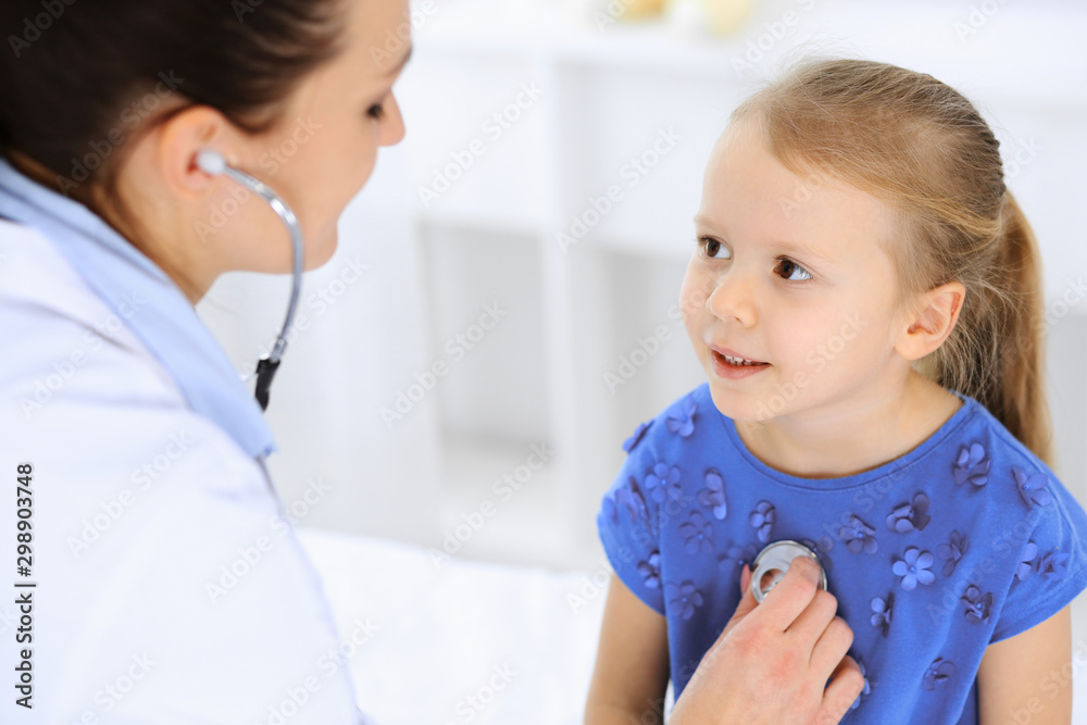 Doctor examining a little girl by stethoscope. Happy smiling child patient at usual medical inspection. Medicine and healthcare concepts Doctor examining a little girl by stethoscope. Happy smiling child patient at usual medical inspection. Medicine and healthcare concepts
