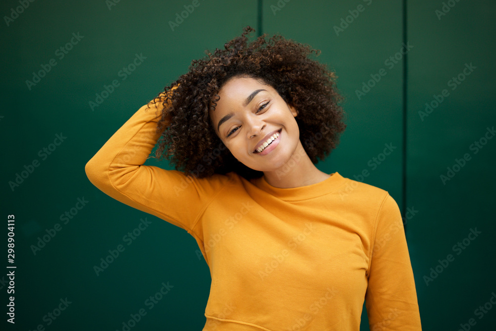 cheerful young african american woman with hand in hair by green background cheerful young african american woman with hand in hair by green background