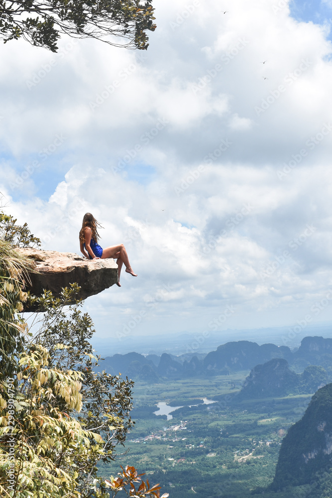 Life on the edge - woman on top of rock on mountain
