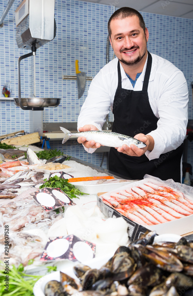 Positive seller in black apron showing fish