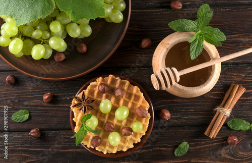 .waffles with grapes and honey on a wooden background