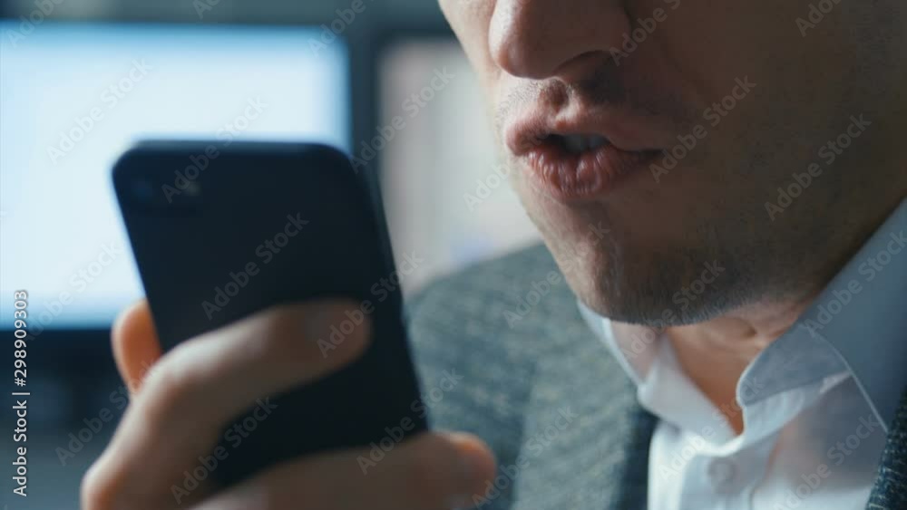Aggressive businessman talking on a video call on a mobile phone. The man screams furiously and shows aggression to the interlocutor. Office background. Stress at work.