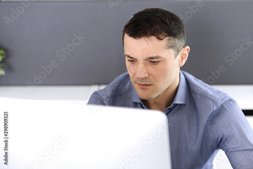 Businessman working with computer in modern office. Headshot of male entrepreneur or company director at workplace. Business concept