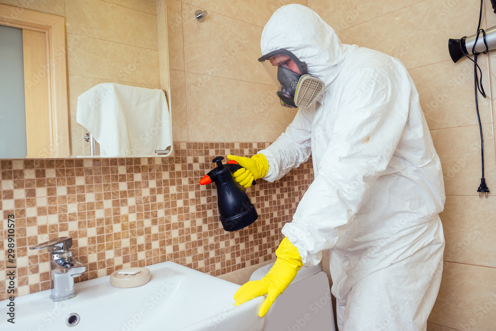 pest control worker spraying pesticides with sprayer in bathroom:processing the toilet and shower
