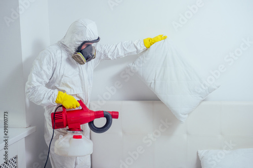 pest control worker lying on floor and spraying pesticides in bedroom