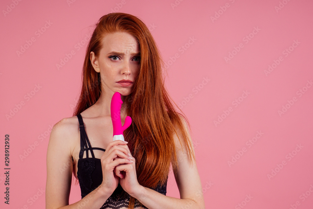 frustrated beautiful redhaired ginger woman in sexy black linen lace holding vibro dildo and disappointment feeling in studio pink background frustrated beautiful redhaired ginger woman in sexy black linen lace holding vibro dildo and disappointment feeling in studio pink background
